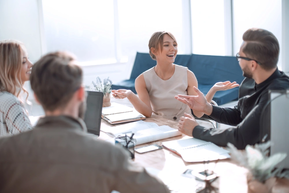 © ASDF / Adobe Stock Eine Gruppe junger Geschäftsleute sitzen an einem Schreibtisch und diskutieren ein Projekt.